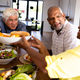 Smiling biracial senior man giving bread to woman while having lunch at dining table in nursing home - PhotoDune Item for Sale