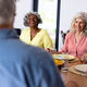 Happy multiracial senior friends talking while sitting at dining table in nursing home - PhotoDune Item for Sale
