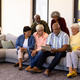 Multiracial seniors looking at digital tablet using by male friend while sitting on sofa - PhotoDune Item for Sale