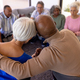 Rear view of multiracial senior man embracing woman in group therapy session at nursing home - PhotoDune Item for Sale