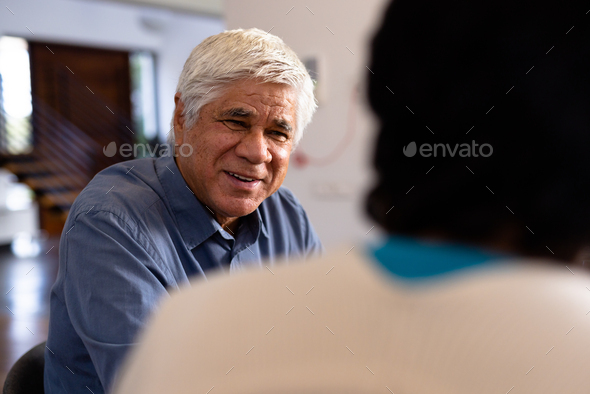 Smiling biracial senior man talking with female friend while sitting for lunch in nursing home - Stock Photo - Images