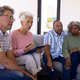 Multiracial female therapist sitting with seniors on sofa in therapy session at retirement home - PhotoDune Item for Sale