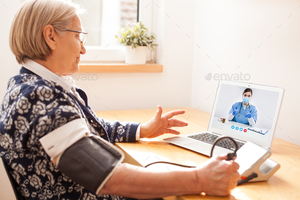 Elderly senior woman using sphygmomanometer blood pressure monitor to measure heart rate pulse - Stock Photo - Images