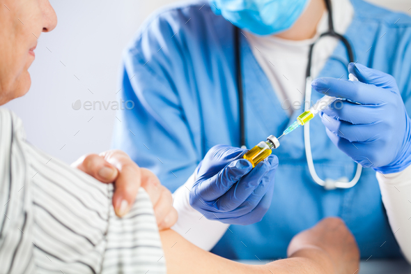 Female GP doctor holding ampoule vial with yellow liquid - Stock Photo - Images