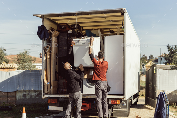 3 colleagues of a moving company load a dishwasher onto the truck