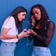Two friends of different ethnicity listen to music in front of a blue wall. - PhotoDune Item for Sale