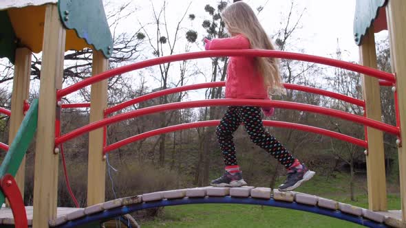 Junior Schoolgirl with Long Fair Hair Climbs Up Attraction alt