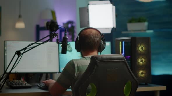 Back Shot of Streamer Man Playing on Powerful Computer Shooter Video Game alt