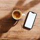 Cup of coffee and smartphone with blank white mockup screen on home office work desk, top view - PhotoDune Item for Sale
