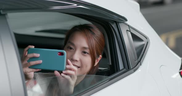 Woman use of mobile phone for taking photo on car