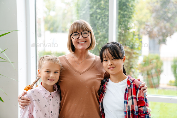White mature teacher smiling while hugging her students
