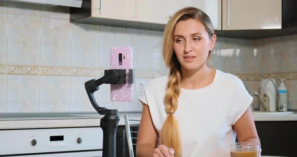 Blogger Looks in Smartphone Camera and Drinks Milk Coffee alt