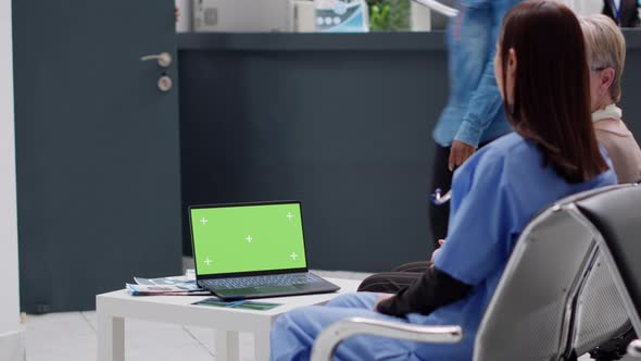 People Sitting in Waiting Area with Greenscreen Template on Laptop alt