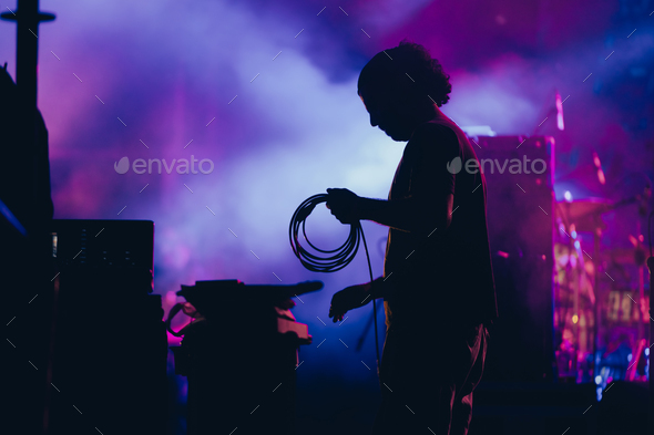 Silhouette of a stage worker standing on a stage with cables