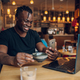 African american man using laptop while drinking coffee in a cafe - PhotoDune Item for Sale