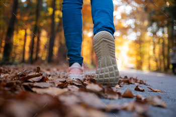Low angle view of woman walking through autumn forest