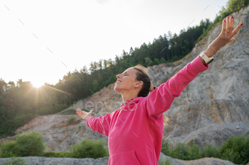 Young woman enjoying life standing outside with spread arms