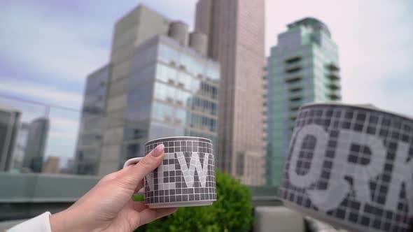 Couple Clink Cups with New York Against the Background of Manhattan Skyscrapers