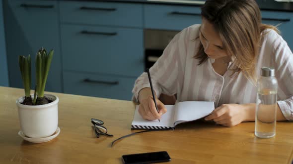 Young Woman Writing Ideas to Notebook