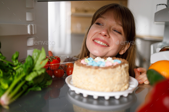 Satisfied woman looking at the cake in the fridge