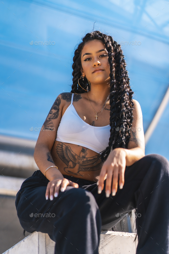 Young woman of black ethnicity with long braids and with tattoos, looking  at camera Stock Photo by Unai82