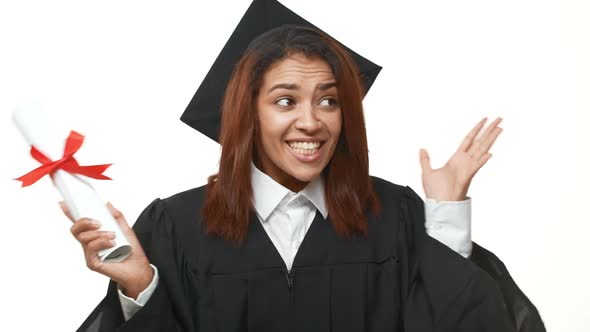 Very Happy African American Graduate Female Student in Academic Dress Rejoicing Holding Her Diploma alt