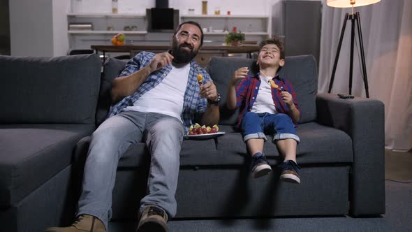 Joyful Father and Son Viewing Comedy Show on Tv alt