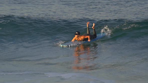 A young woman in a wetsuit surfing on a longboard surfboard. alt