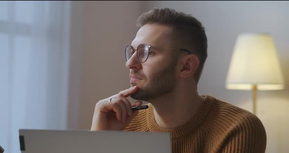 Man Is Working on Project at Home Freelance and Parttime Job Sitting in Front of Notebook in Room alt
