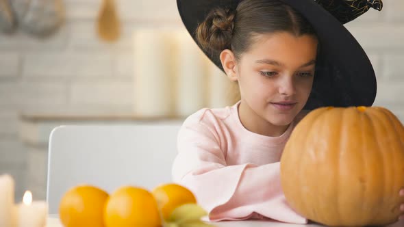 Cute Girl in Witch Costume Showing Jack Pumpkin and Smiling, Preparing for Party alt