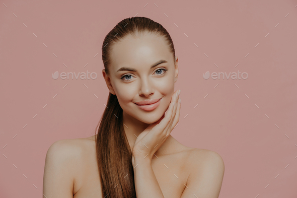 Portrait of good looking female has long straight hair combed in pony tail