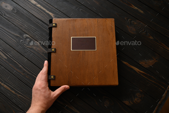 An old photo album with a wooden cover and a shield on a rustic table. free logo