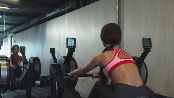 The Pumped-up Girl Does Exercises on the Rowing Machine