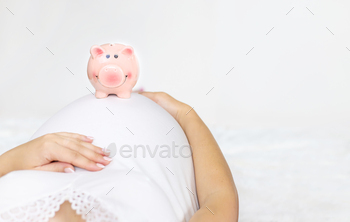 A pregnant woman is holding a piggy bank. Selective focus.
