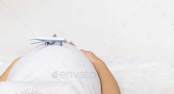 A pregnant woman is holding a plane. Selective focus.