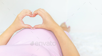 A pregnant woman is holding a heart. Selective focus.