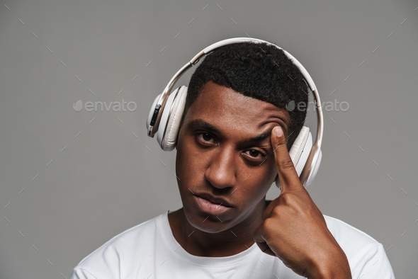 Young black man in headphones pointing finger at his temple