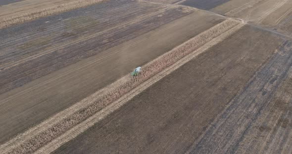 Combine Harvester Collecting Corn Cobs On The Field - aerial drone shot alt