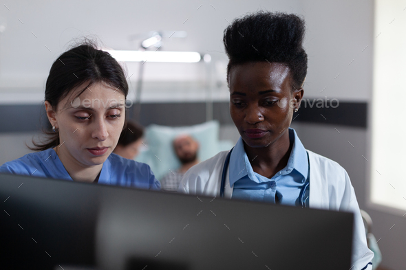 Nurse and african american doctor using personal computer for clinical imagistic