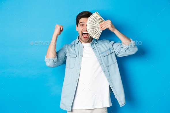 Successful young man earn money, making fist pump and showing cash, winning prize or receive credit