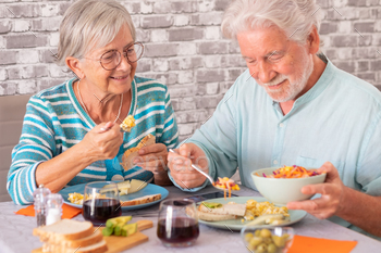 Smiling caucasian senior couple sitting at table having brunch together at home