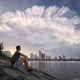 Man sitting on waterfront and looking at dramatic sky - PhotoDune Item for Sale
