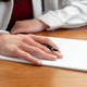 Female doctor hand with a pen on a blank paper, close up, wooden office table. - PhotoDune Item for Sale