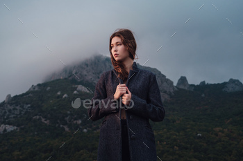 Asian woman in a gray coat enjoying the view in the mountains