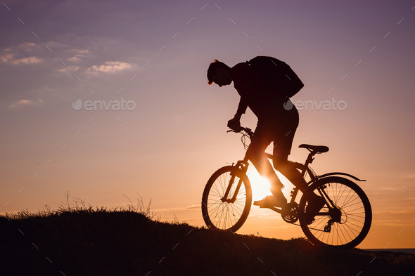 Silhouette of cyclist in motion at beautiful sunset. - Stock Photo - Images