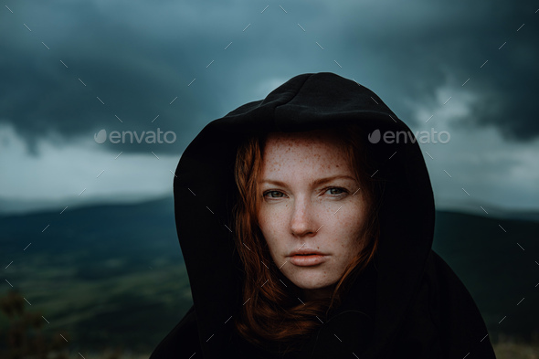 woman in black hood stands in the rain
