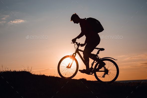 Silhouette of cyclist in motion at beautiful sunset. - Stock Photo - Images