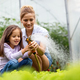 Happy family working in organic greenhouse. Woman and child growing bio plants in farm garden - PhotoDune Item for Sale