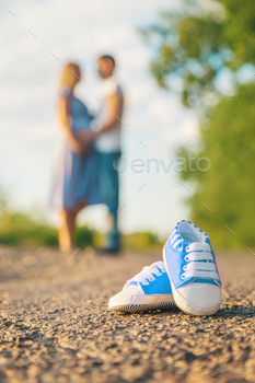 Pregnant woman and man baby shoes. Selective focus.