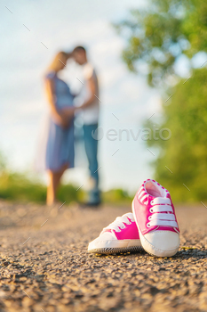 Pregnant woman and man baby shoes. Selective focus.